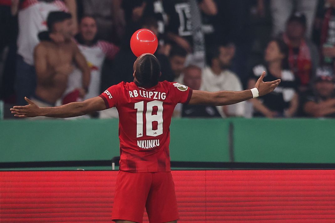 Leipzigs Torschütze Christopher Nkunku bläst einen roten Ballon auf. RB hat erneut den DFB-Pokal gewonnen.