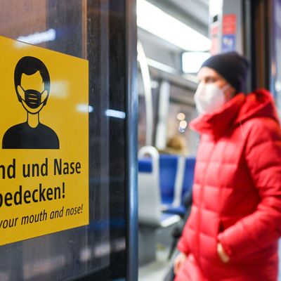 Eine Frau, die eine FFP2-Maske trägt, in eine Trambahn ein. 