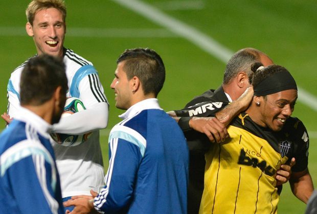 
                <strong>Idole hautnah erleben</strong><br>
                Der Ronaldinho-Doppelgänger sorgt bei den Argentiniern für gute Laune. Andere Fans schaffen es ebenfalls auf das Feld. Ein anderer Anhänger putzt Messi mit einem Tuch die Schuhe. Weitere Fans tummeln sich auch auf dem Spielfeld und begrüßen ihre Stars.
              