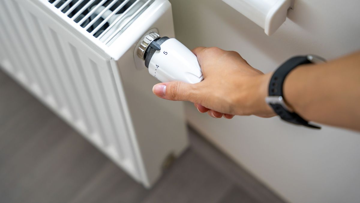 A woman's hand turns the battery heating knob. Heating in an apartment, at home. Heating prices.