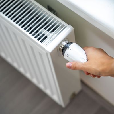 A woman's hand turns the battery heating knob. Heating in an apartment, at home. Heating prices.