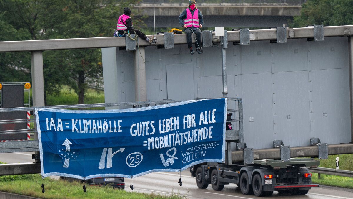 Klimaaktivisten demonstrieren mit einem Plakat auf der A9 nahe der Allianz Arena gegen die IAA.