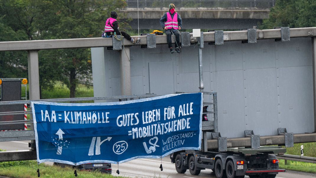 Klimaaktivisten demonstrieren mit einem Plakat auf der A9 nahe der Allianz Arena gegen die IAA.
