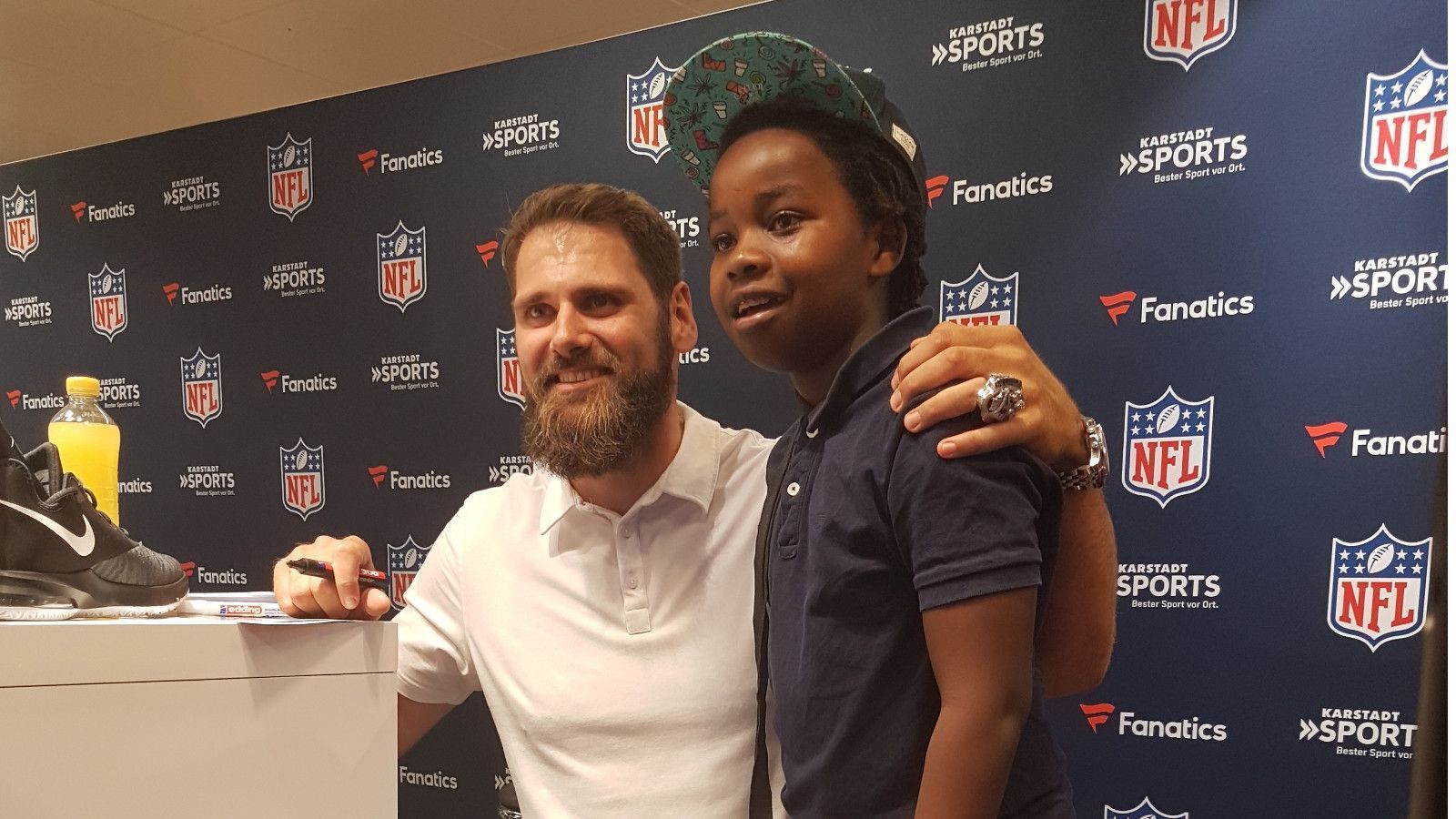 
                <strong>Deutsche NFL-Stars zur Autogramm-Stunde in München</strong><br>
                Am meisten freuen sich die kleinsten Fans. Für die geht Vollmer sogar in die Knie. Sonst wäre das Foto auch schwierig. "Er wirkt super nett und wirklich sympathisch. Er sitzt hier zwei Stunden und macht Fotos, trotzdem wirkt seine Art nicht gespielt oder aufgesetzt", meint ein Vater.
              