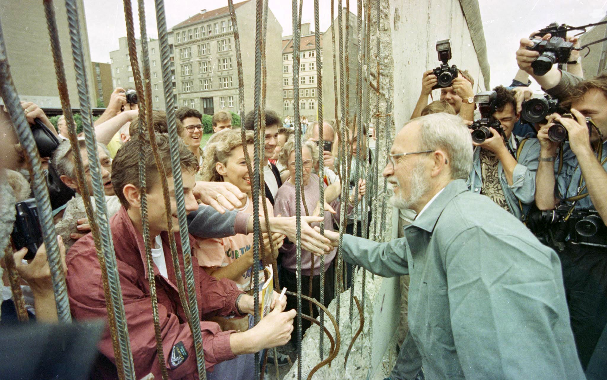 Der ostdeutsche Ministerpräsident Lothar de Maiziere schüttelt am 15. Juni 1990 Berliner Bürgern durch ein großes Loch in der Berliner Mauer in der Nähe des Checkpoint Charlie die Hand.