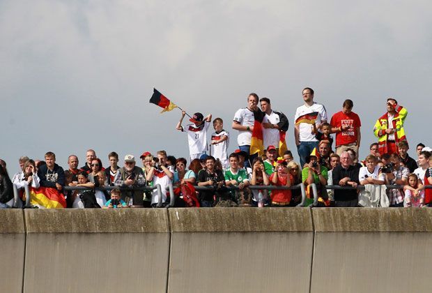 
                <strong>Wer erhascht den ersten Blick?</strong><br>
                Auch vor dem Flughafen Berlin Tegel sind überall deutsche Fans. Wer erhascht den ersten Blick auf die deutschen Nationalspieler?
              