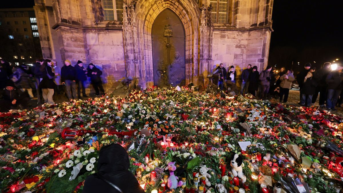 Mehrere Menschen legen Blumen und Kerzen am offiziellen Gedenkort an der Johanniskirche nieder. 