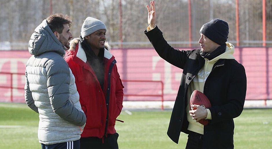 
                <strong>Deshaun Watson besucht Deutschland</strong><br>
                Lewandowski (r.) demonstriert bei eisigen Temperaturen, wie er die Pässe von Watson fangen würde. Javi Martinez (l.) gibt den aufmerksamen Zuhörer.
              