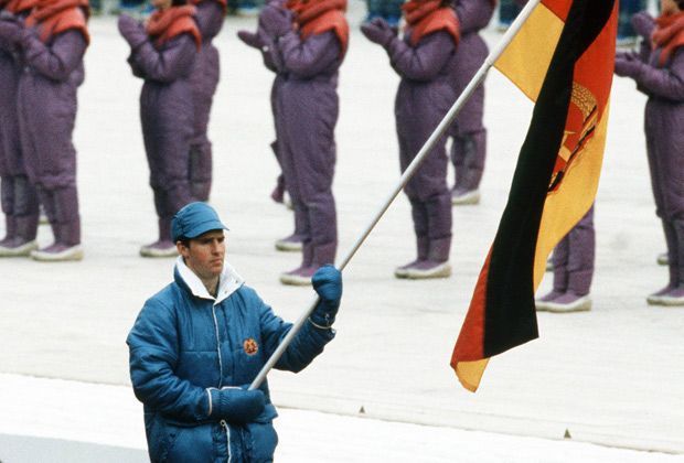 
                <strong>1984 in Sarajevo: Frank Ullrich (DDR)</strong><br>
                In einem knallblauen Outfit trat der damals 26 Jahre alte Frank Ullrich als Fahnenträger vor die Menschenmassen. Der Biathlet ging während der Olympischen Winterspiele in Sarajevo jedoch leer aus.
              