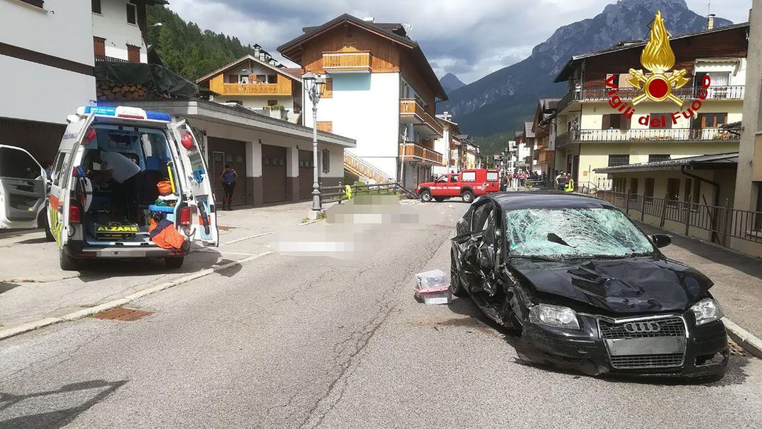 Ein Krankenwagen und das Auto der Deutschen stehen nach dem Unfall neben den Opfern (gepixelt), die auf einer Straße liegen.