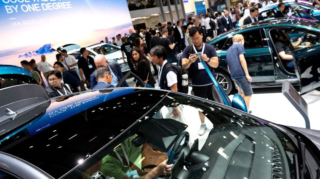 Messebesucher schauen sich während der Automobil-Ausstellung IAA MOBILITY 2023 in München am Messestand von BYD die aktuellen Autos aus China an. 