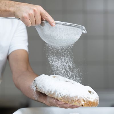 Ein Bäcker bestreut im Dresdner Backhaus einen Christstollen mit Puderzucker.