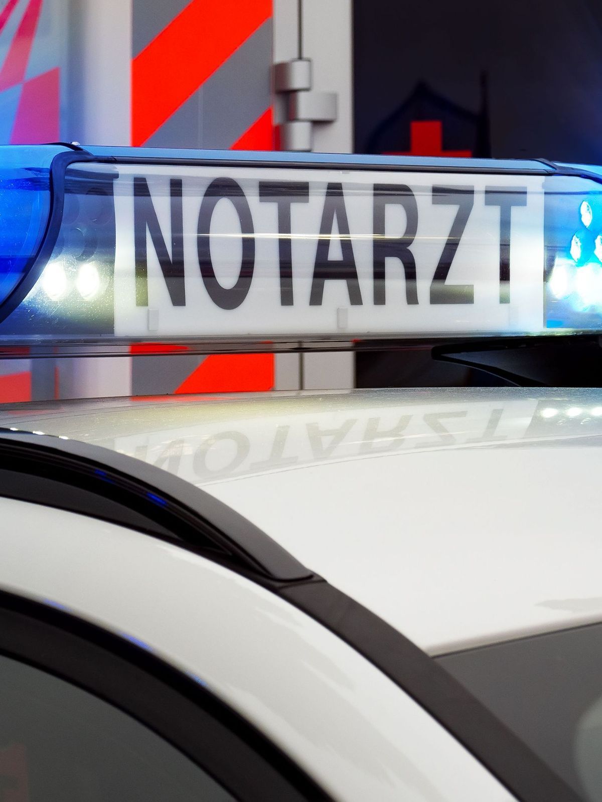 Teilansicht Feuerwehreinsatzfahrzeug mit Blaulicht und Notarztfahrzeug. Notruf 112