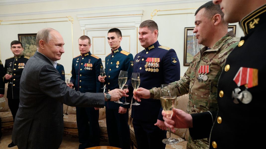 Russlands Präsident Wladimir Putin (l) stößt mit russischen Soldaten während eines Treffens in der staatlichen Residenz Nowo-Ogarjowo außerhalb von Moskau an.  