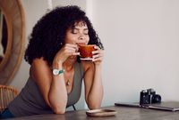 Frau trinkt mit geschlossenen Augen eine Tasse Kaffee