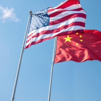 US China flags wave symbolizing international relations against a clear blue sky representing diplomacy