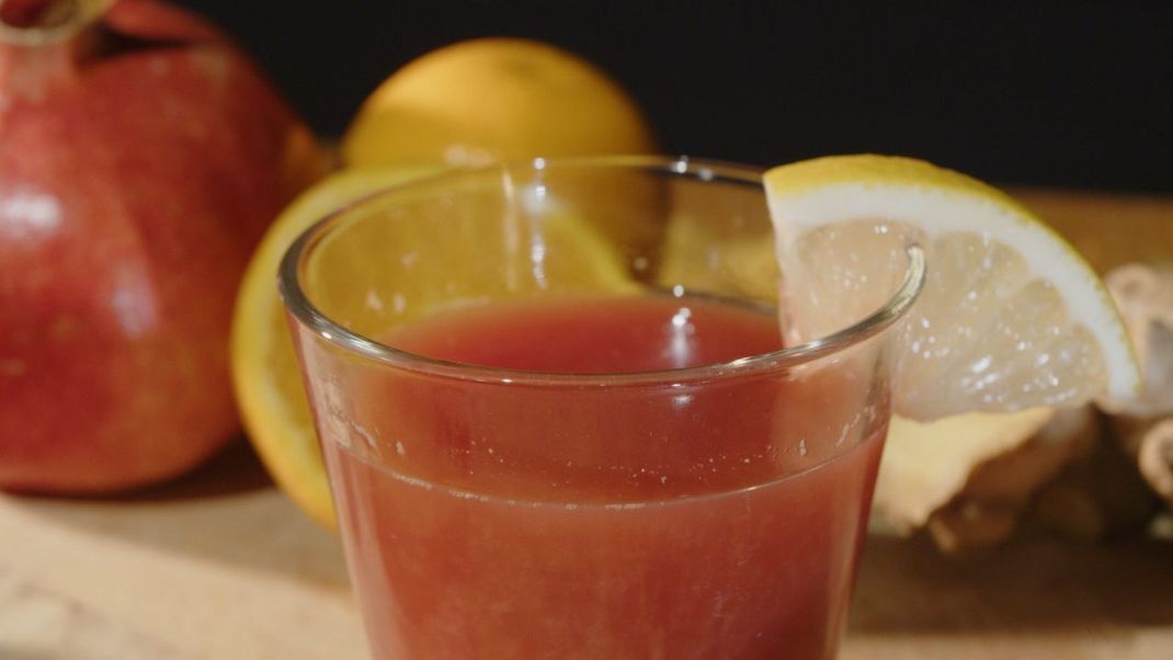 Der Granatapfel-Ingwer-Shot enthält auch Orangen- und Zitronensaft. Zur Dekoration kannst du einen Zitronenschlitz an den Glasrand stecken.