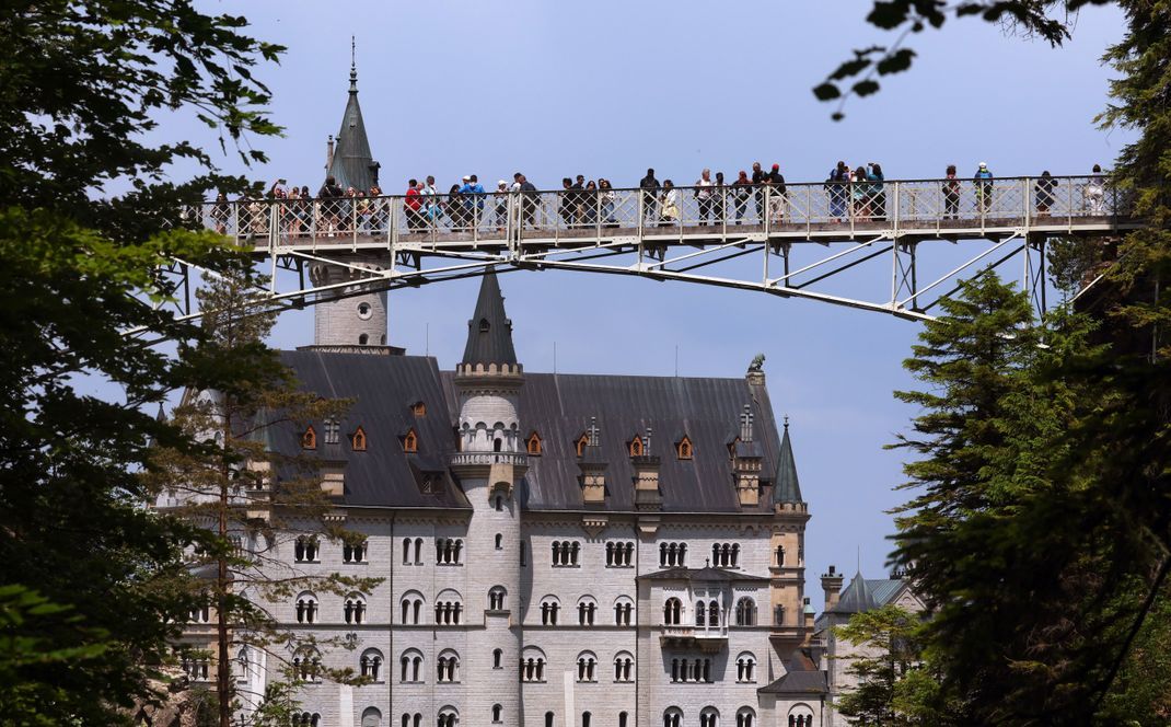 Touristen stehen auf der Marienbrücke vor dem Schloss Neuschwanstein.