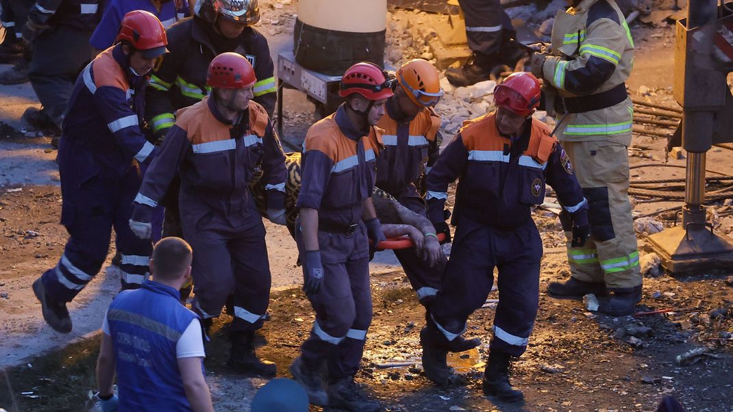 Durch eine Explosion wurde ein mehrstöckiges Wohnhaus stark zerstört. Rettungskräfte bergen Verletze.