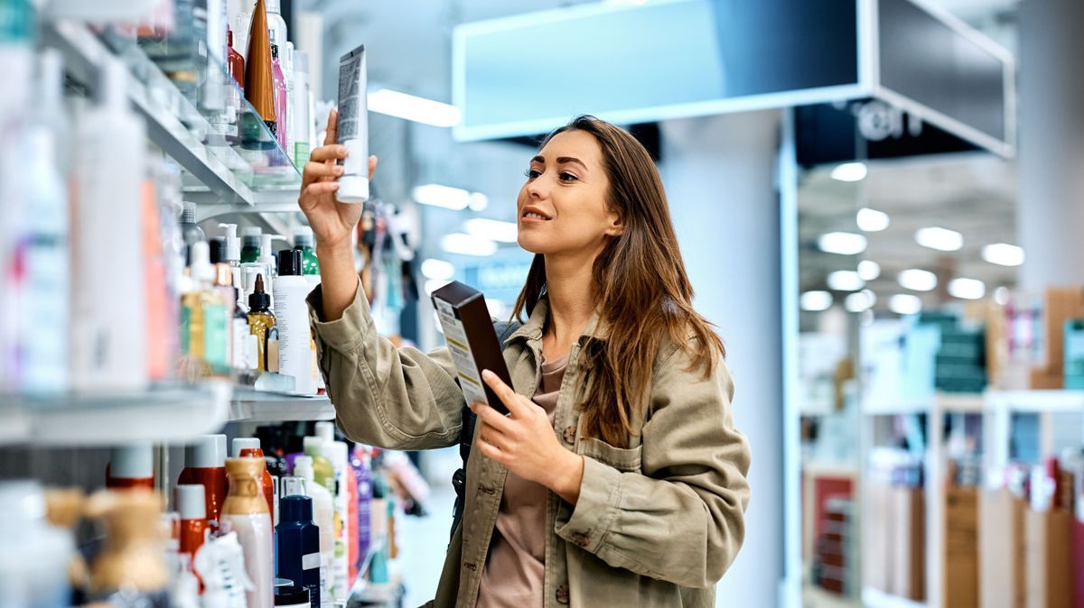 Smiling woman looking for skin care products at cosmetic store.