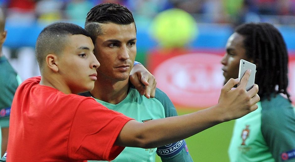 
                <strong>Selfie-Time für CR7</strong><br>
                Selfie-Time für CR7: Cristiano Ronaldo hier CR7 da. Der Portugiese sorgt wie immer für Aufsehen und ist natürlich auch bei den Fans absolut gefragt. Zwei Anhänger geben für ein Foto mit ihrem Idol alles: Nach dem Vorrundenspiel gegen Österreich und vor dem Halbfinal-Duell gegen Wales schleicht sich jeweils ein Ronaldo-Fan an den Ordnern vorbei auf den Platz, um ein Selfie mit dem Superstar zu machen. Von Ärger bei Ronaldo ist dabei keine Spur - der 31-Jährige setzt sich bei den Ordnern sogar noch für die beiden Selfie-Jäger ein, damit in Ruhe ein Foto aufgenommen werden kann.
              