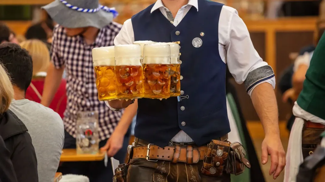 Ein Kellner trägt Bierkrüge auf dem Oktoberfest.