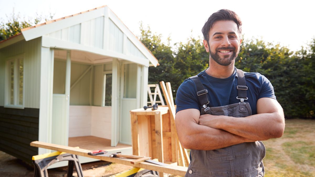 Portrait eines Heimwerkers oder Handwerkers, der ein Gartenhaus in seinen Garten gebaut hat.