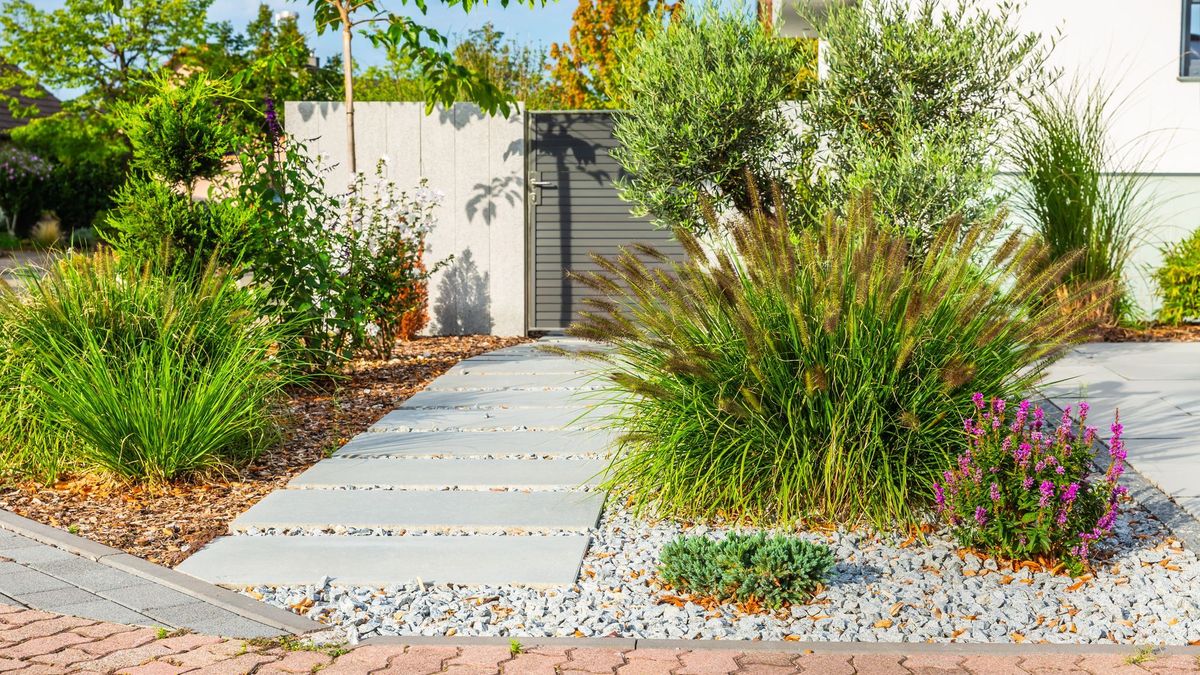 Der Vorgarten eines modernen Hauses, Gartendetails mit bunten Pflanzen, trockene Grasbeete, umgeben von grauen Felsen.