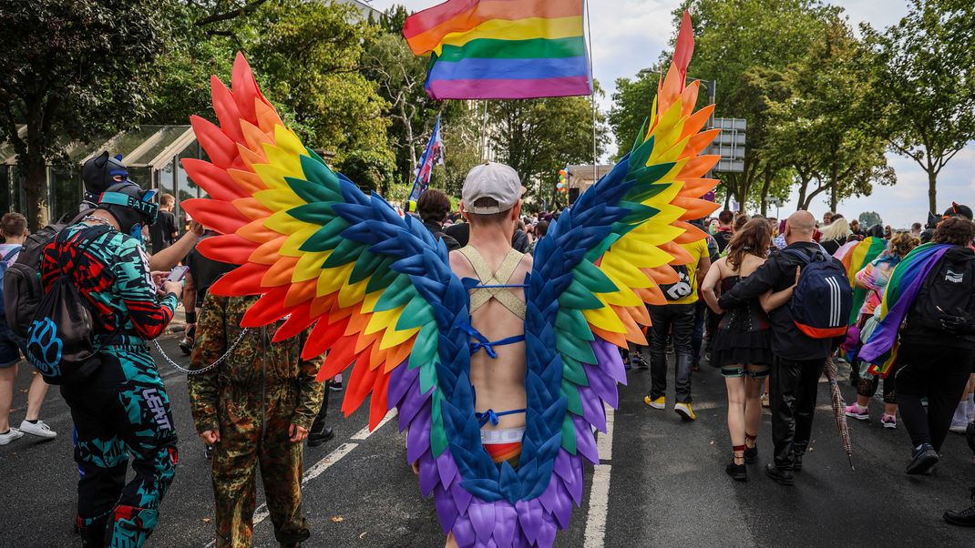 Ein Teilnehmer des Christopher Street Day (CSD) in Bremen trägt regenbogenfarbene Flügel.