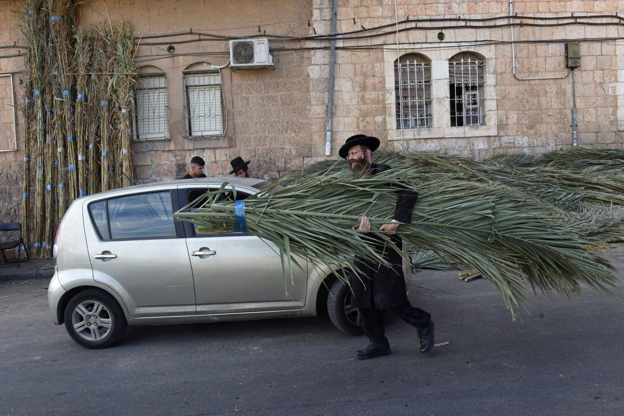 Dieser ultraorthodoxe Jude trägt Palmwedel für seine Laubhütte zu Sukkot, dem Laubhüttenfest. Jüdinnen und Juden danken Gott für die Ernte und gedenken des Auszugs aus Ägypten. 