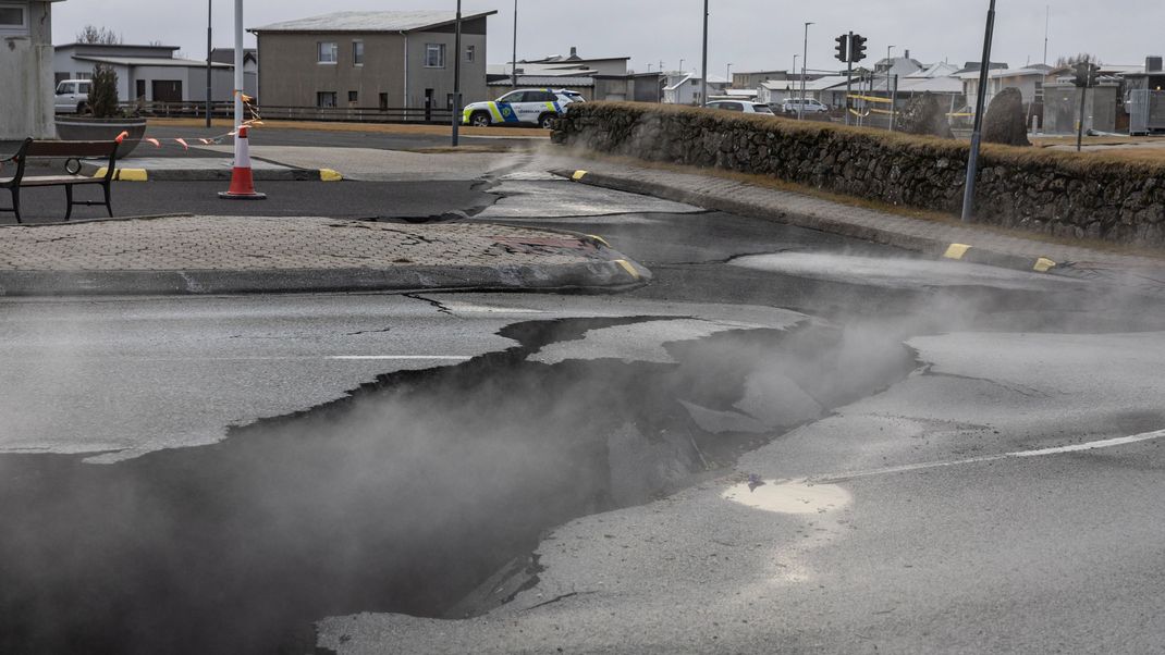 Rauch steigt aus dem Riss in einer Straße im Fischerdorf Grindavik, das aufgrund vulkanischer Aktivität evakuiert wurde.