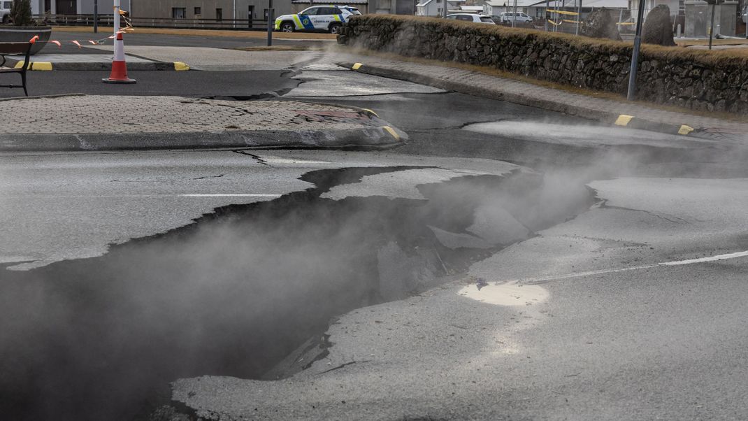 Rauch steigt aus dem Riss in einer Straße im Fischerdorf Grindavik, das aufgrund vulkanischer Aktivität evakuiert wurde.