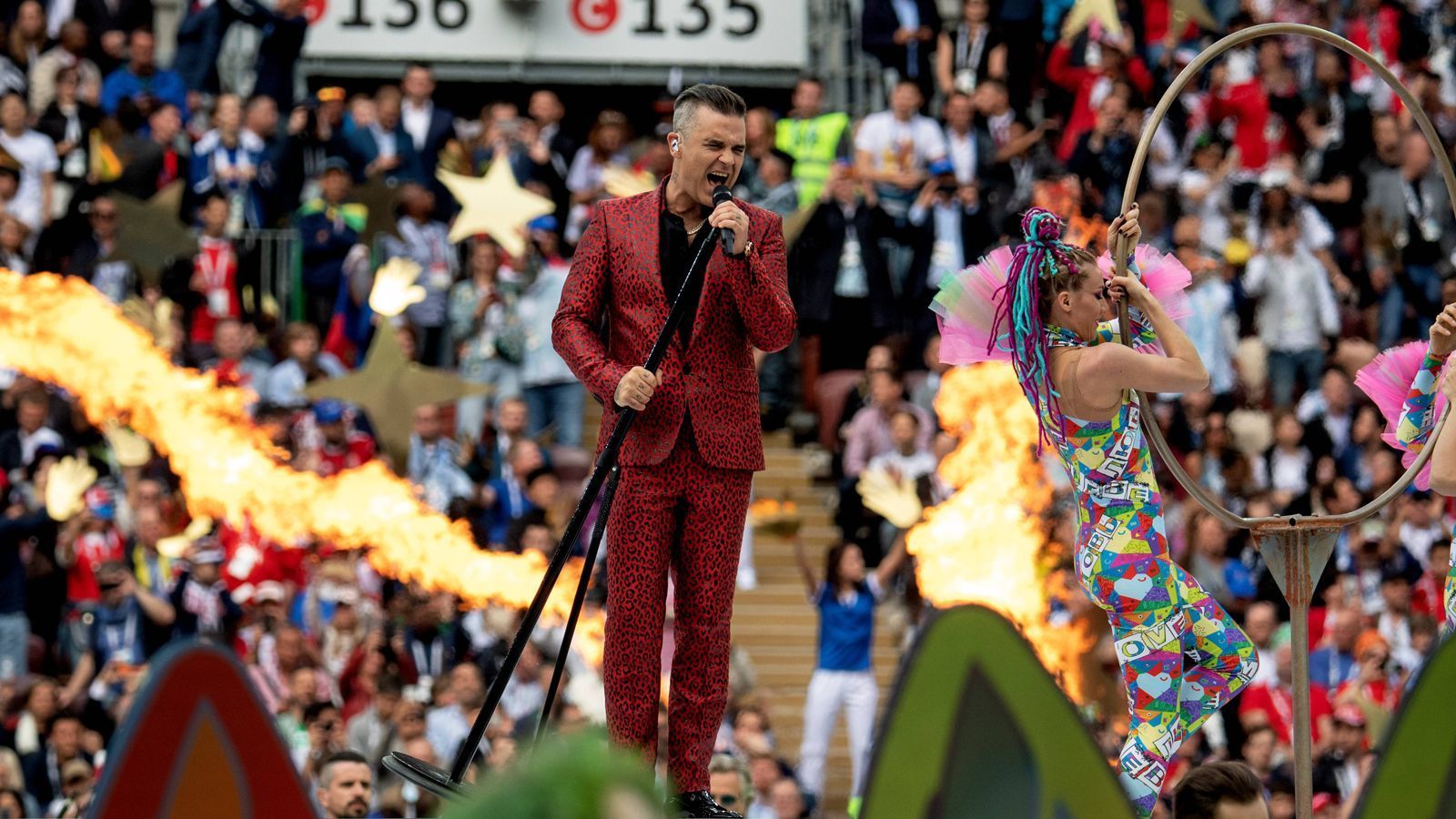 
                <strong>WM 2018: So lief die Eröffnungsfeier</strong><br>
                Robbie Williams brachte seine größten Hits mit wie "Feel" oder "Let me entertain you". Letzteren Song setzte er in die Tat um, riss die Fans im Stadion mit. Stilecht im weinroten Leoparden-Anzug.
              