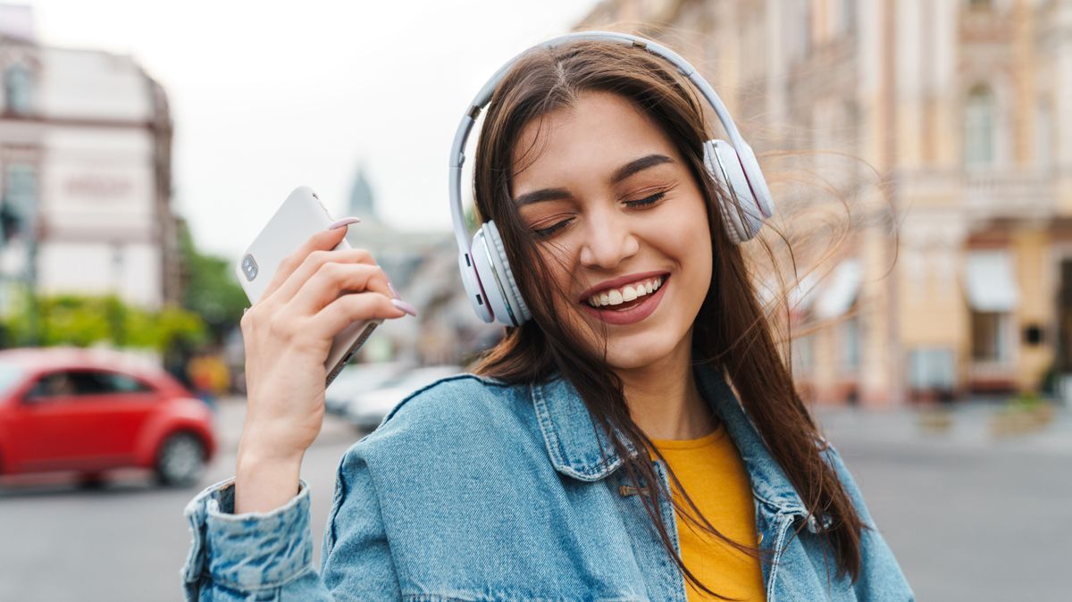 Image of woman listening music with smartphone and wireless headphones