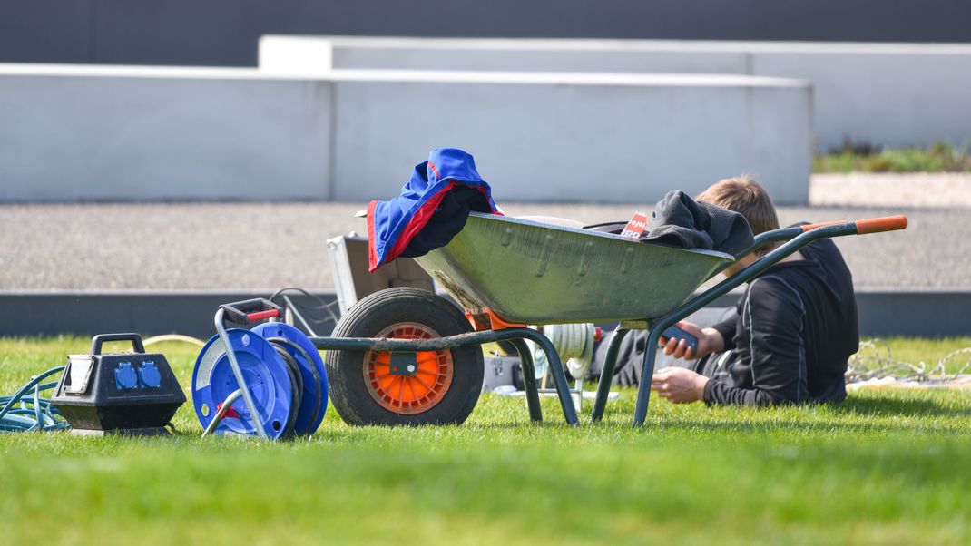 Ein Arbeiter macht auf dem Gelände der Landesgartenschau neben einer Schubkarre eine Pause. 