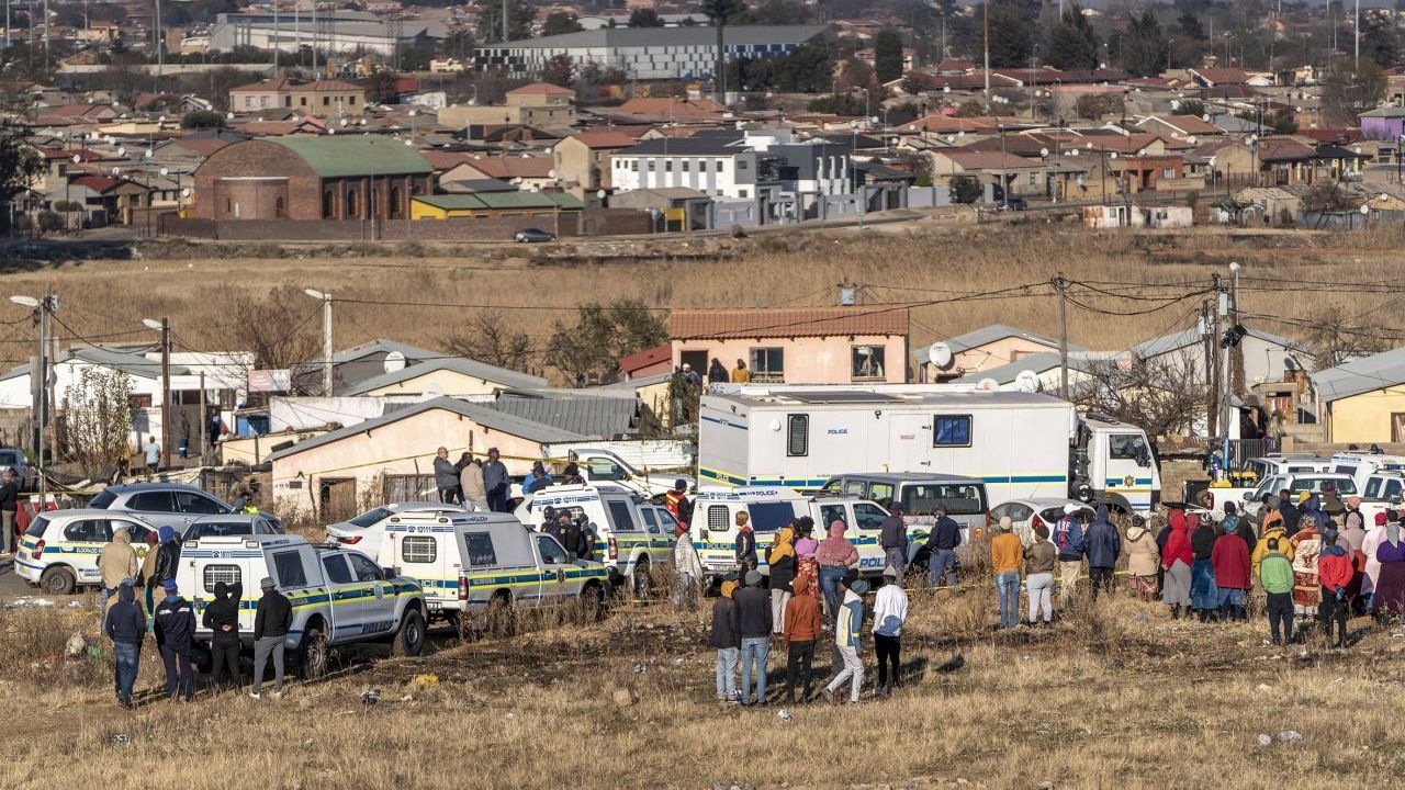 Das Soweto (South Western Townships) ist eine (frühere) Township von Johannesburg. Auf dem Foto siehst du, wie sich Menschen im Juli 2022 nach einer nächtlichen Schießerei in einer Bar versammelt haben.