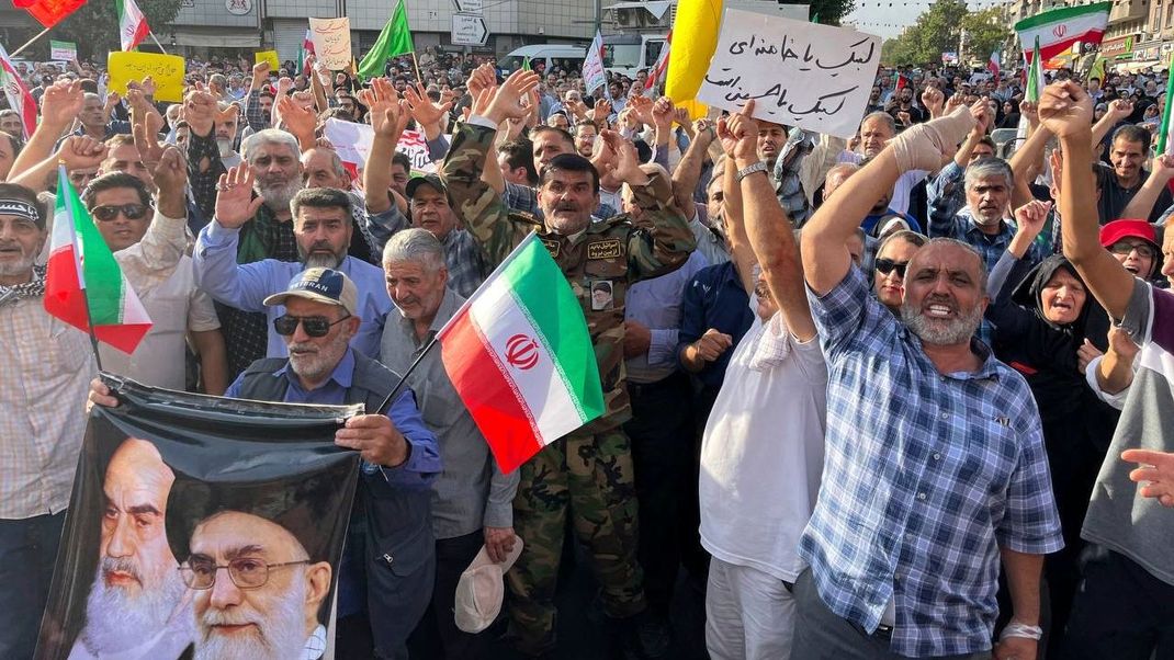 Demonstranten tragen iranische Nationalflaggen und ein Poster des verstorbenen Revolutionsgründers Ayatollah Khomeini (l)und des Obersten Führers Ayatollah Ali Khamenei, während sie nach den Angriffen auf Atomanlagen im Iran Slogans gegen die USA und Israel skandieren.