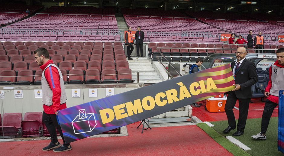 
                <strong>Werbung für die Abstimmung</strong><br>
                Im Stadion wären wohl auch während eines normal ausgetragenen Spiels politische Botschaften gezeigt worden. Hier tragen Ordner einen Aufsteller mit der Aufschrift "Demokratie", einer Wahlurne für das Referendum und der Landesflagge Kataloniens in den Innenraum.
              