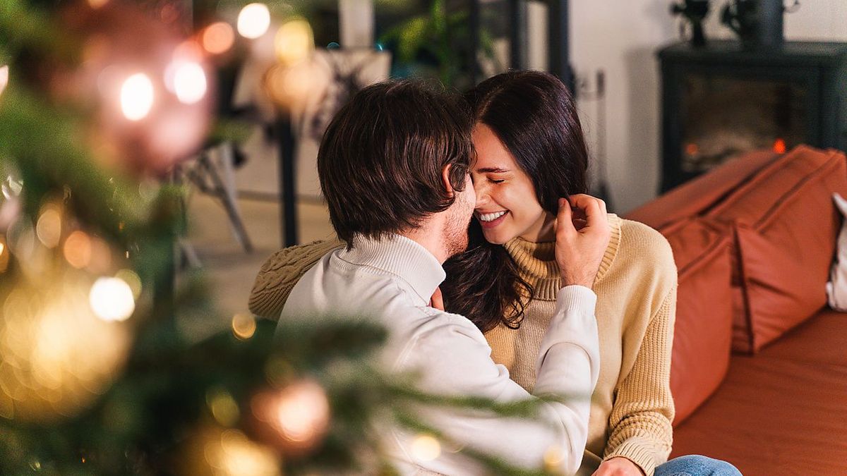 Happy beautiful couple of lovers celebrating Christmas at home - Winter holiday season, celebration of xmas eve in a decorated apartment