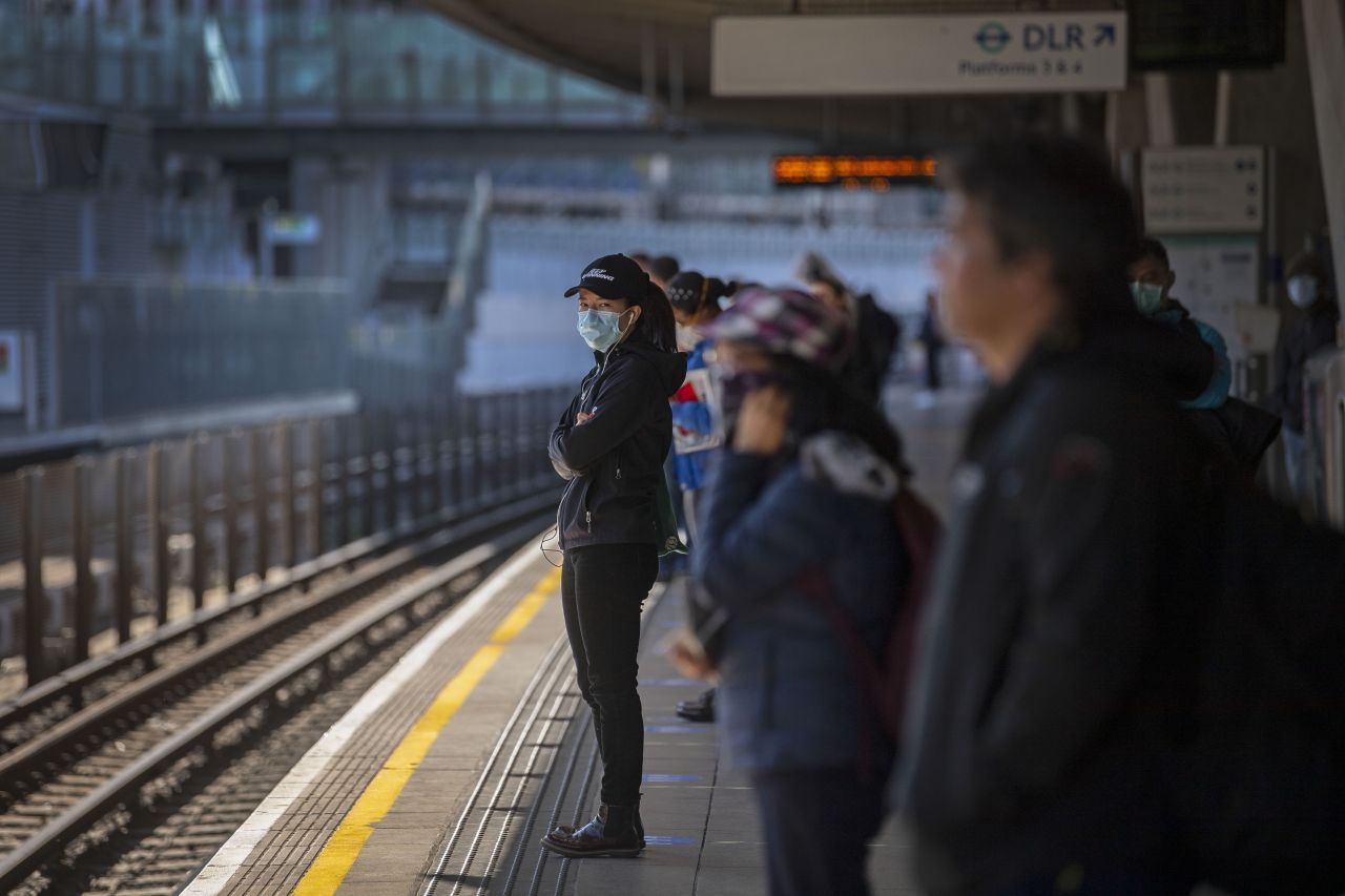 Großbritannien, London: Fahrgäste stehen auseinander und tragen Gesichtsmasken auf einem Bahnsteig in der Londoner U-Bahn-Station Canning Town.