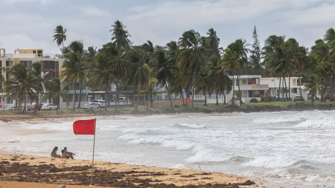 Touristen sitzen am Strand von La Pared, während der Tropensturm "Ernest" vorbeizieht.&nbsp;