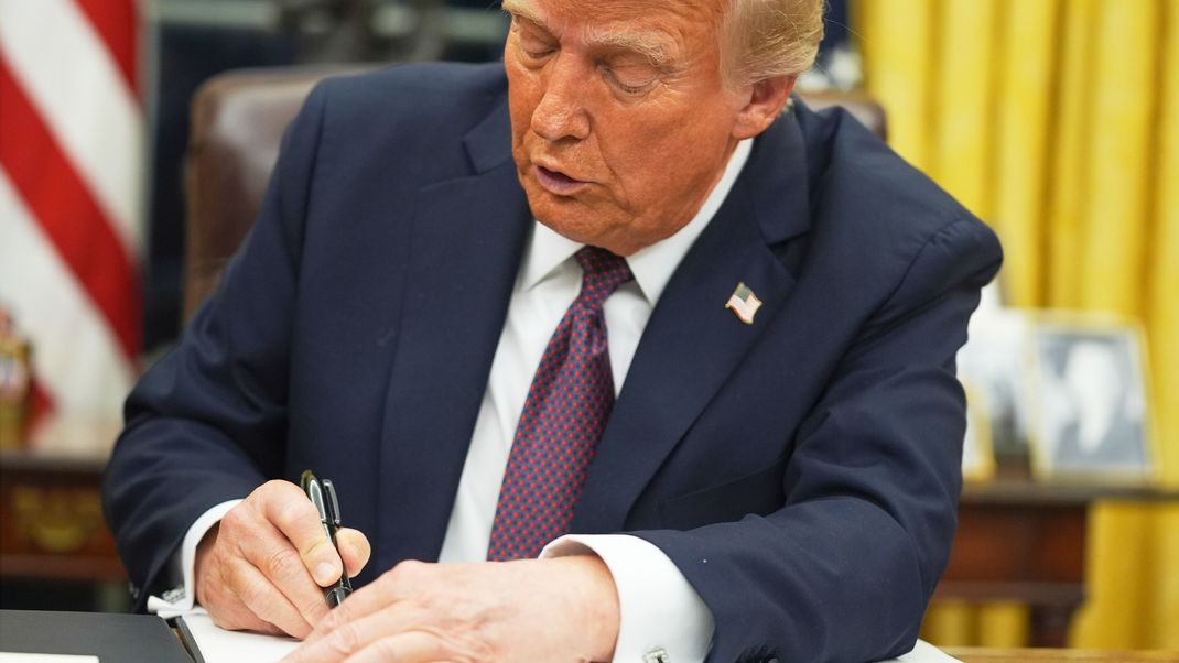 US-Präsident Donald Trump unterzeichnet ein Schriftstück im Oval Office des Weißen Hauses. 