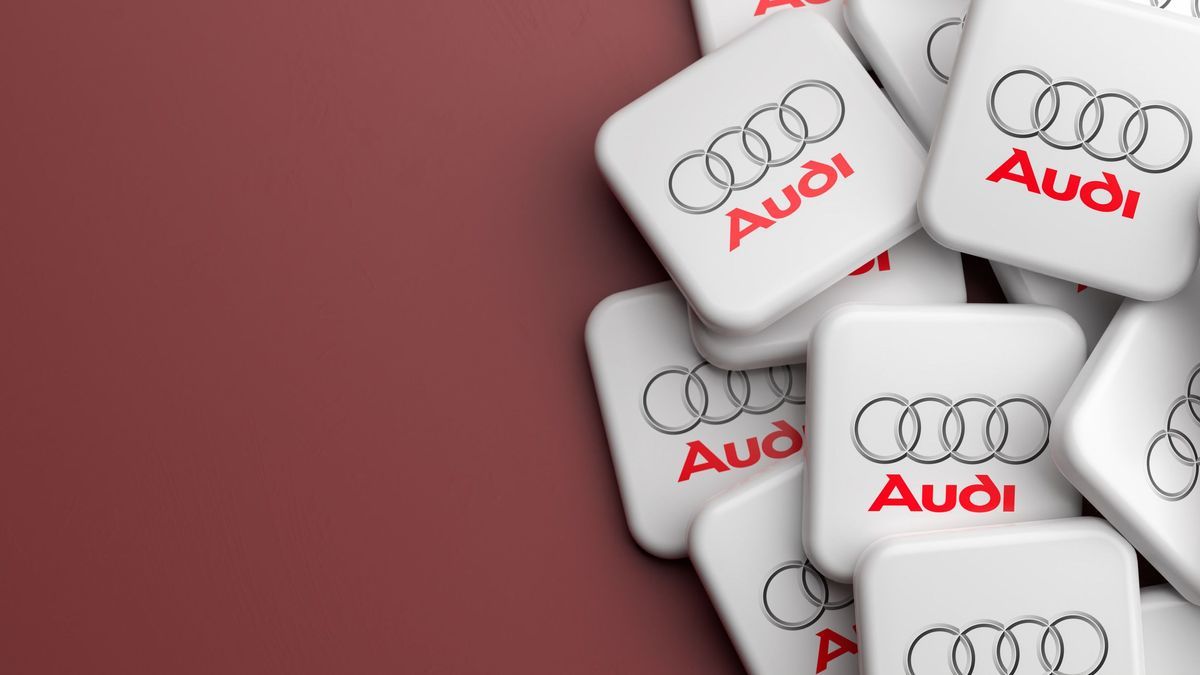 Logos of the German luxury car manufacturer Audi on a heap on a table. Copy space. Web banner format.