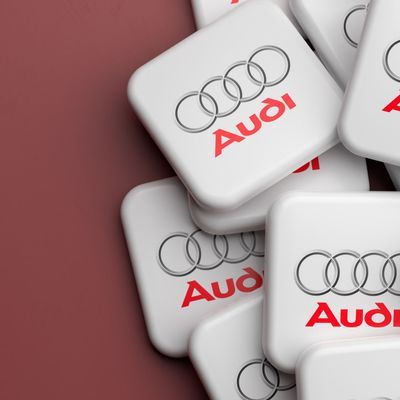 Logos of the German luxury car manufacturer Audi on a heap on a table. Copy space. Web banner format.