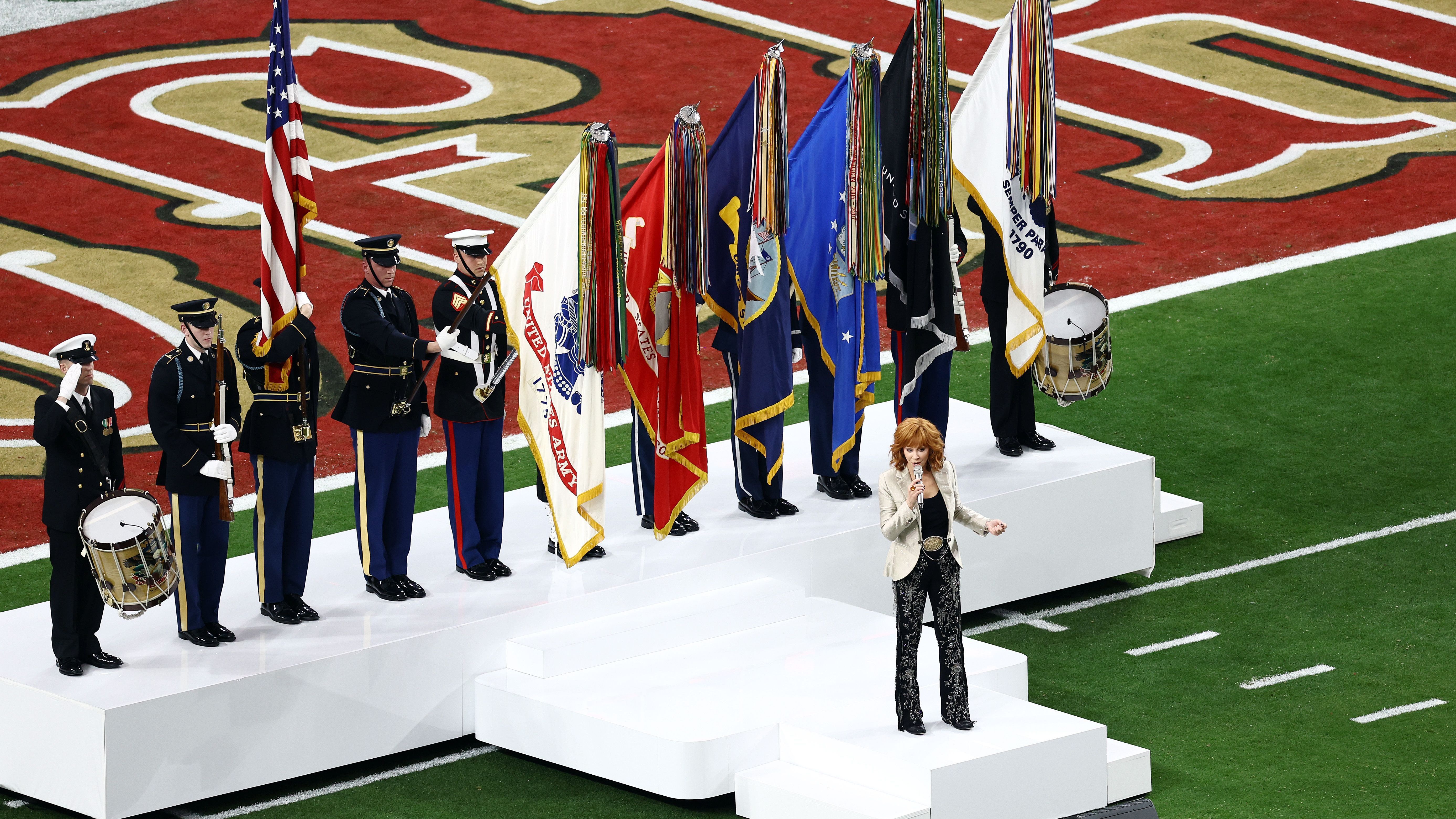 <strong>Reba McEntire singt die Nationalhymne</strong><br>Die Country-Sängerin wird von Soldaten der verschiedenen Waffengattungen begleitet.