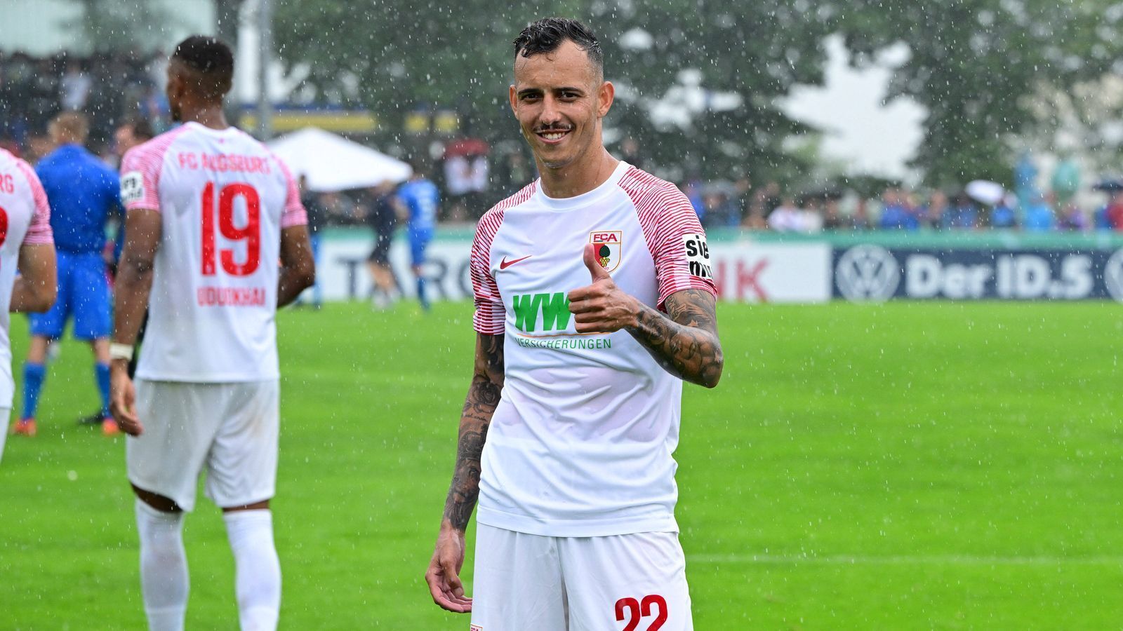 
                <strong>FC Augsburg</strong><br>
                Daumen hoch bei Iago und dem FC Augsburg: Auch in der vergangenen Saison hat sich der FCA in der Bundesliga gehalten und das, obwohl zu Beginn viel dagegen gesprochen hatte. Nach der Saison sorgte der Abtritt von Markus Weinzierl und die Trennung vom oft verletzten Goalgetter Alfred Finnbogason für Unruhe. Der Pflichtspielauftakt bei Blau-Weiß Lohne war nach einigen Anlaufschwierigkeiten letztlich mit 4:0 erfolgreich. Der Kader hat in der Breite qualitativ kaum hinzugewonnen - dazu hat sich Führungsspieler Niklas Dorsch länger verletzt. Für Bundesliga-Trainerneuling Enrico Maaßen wartet eine große Herausforderung. Das Heimspiel gegen den SC Freiburg kann schon Hinweise geben, in welche Richtung es diesmal geht.
              