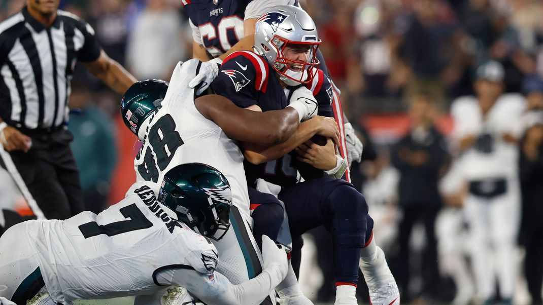 New England Patriots Quarterback Mac Jones (oben r) wird von Philadelphia Eagles Linebacker Haason Reddick (7) und Defensive Tackle Jalen Carter (Ml) zu Fall gebracht.