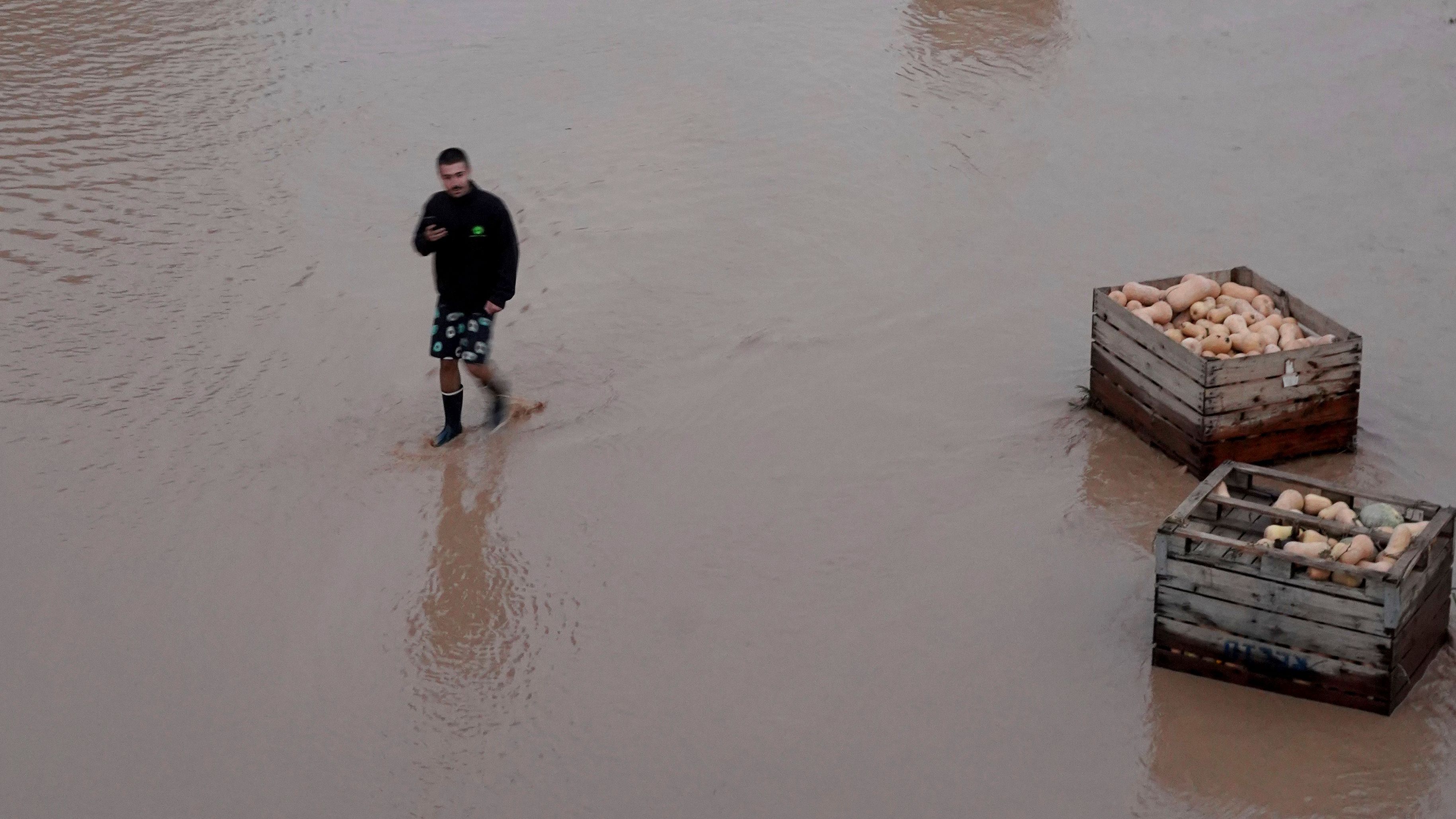 Um homem caminha em uma rodovia inundada perto de Valência.