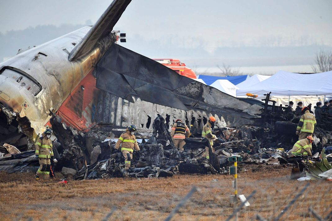 Helfer:innen untersuchen die Wrackteile des verunglückten Flugzeugs.