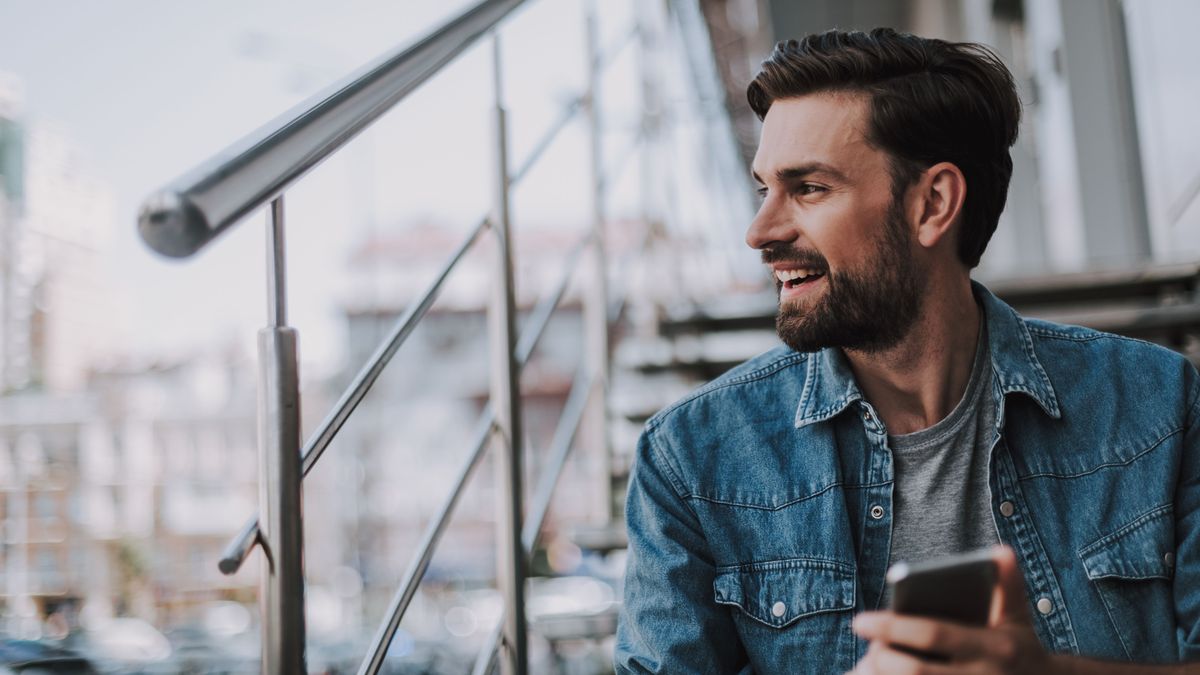 Cheerful man typing in mobile at street